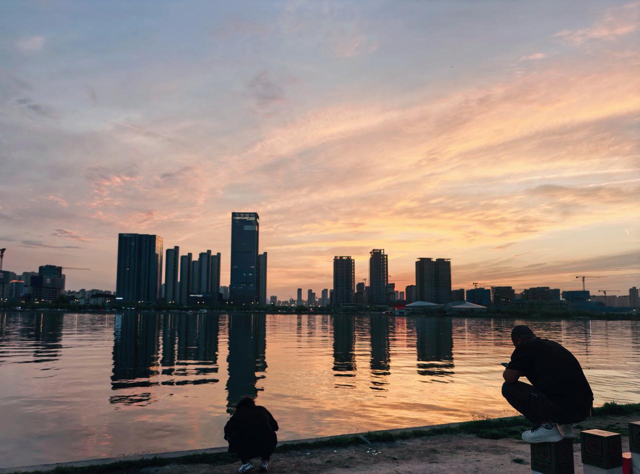 当暮色把城市的钢筋混凝土调成蜜色，云朵便在河面上铺了糖霜，蹲在岸边的人，默默无言