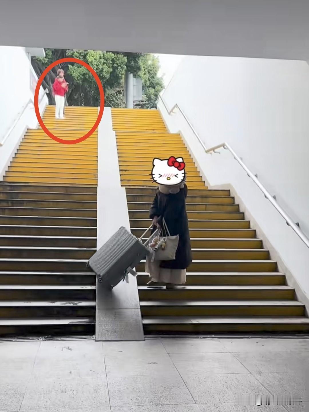 女生拖着行李箱下楼梯，远远站着两个女的在观望，都没有上前帮忙的意愿，包括这个拍视
