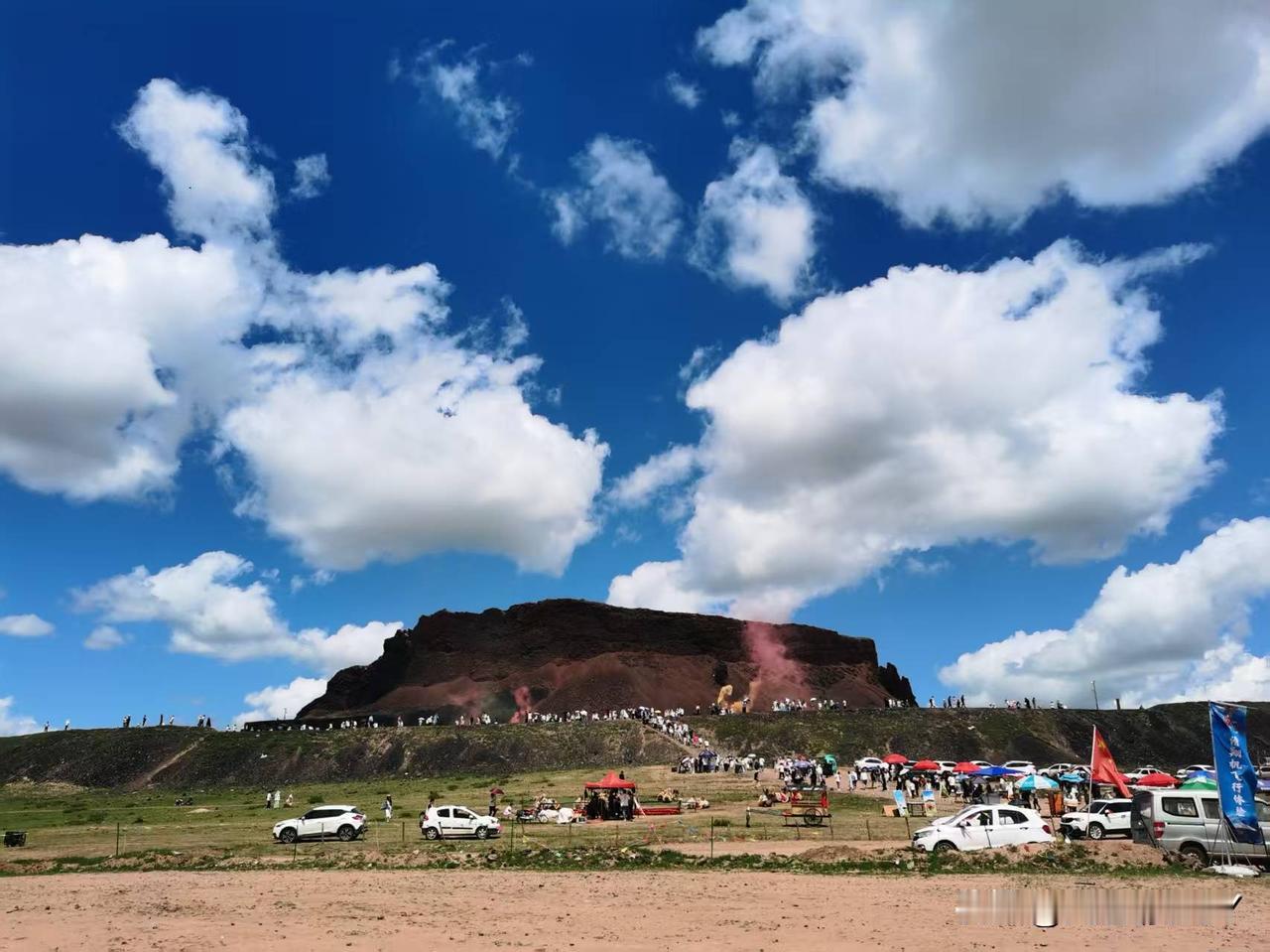 她以陡峭尖山形态突兀于草原之上，奇异的白云飘逸在天空，就像是新疆的棉絮在跳舞；黑