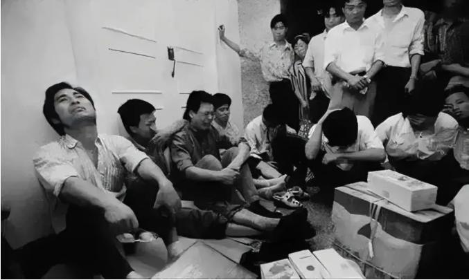 这是一群下岗职工坐在地上痛哭的照片，曾经的“工人老大哥”早已成为过眼云烟，他们的