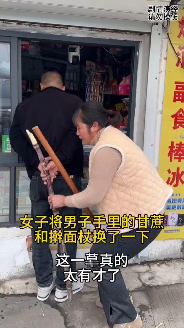 女子将男子手里的甘蔗和擀面杖换了一下，这一幕真的太有才了。
男子拿着甘蔗吃起来，