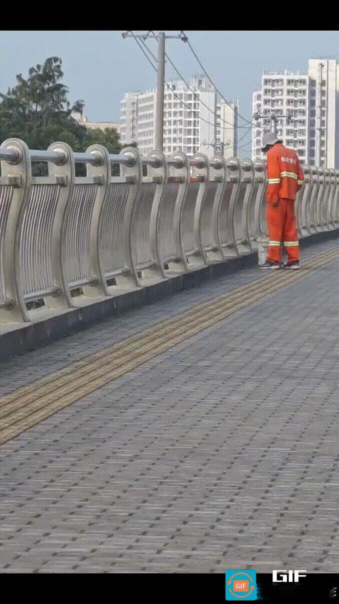 市民早晨去上班，在天桥上拍下的一幕。
环卫工人将天桥上扫好的垃圾装进垃圾桶，然后