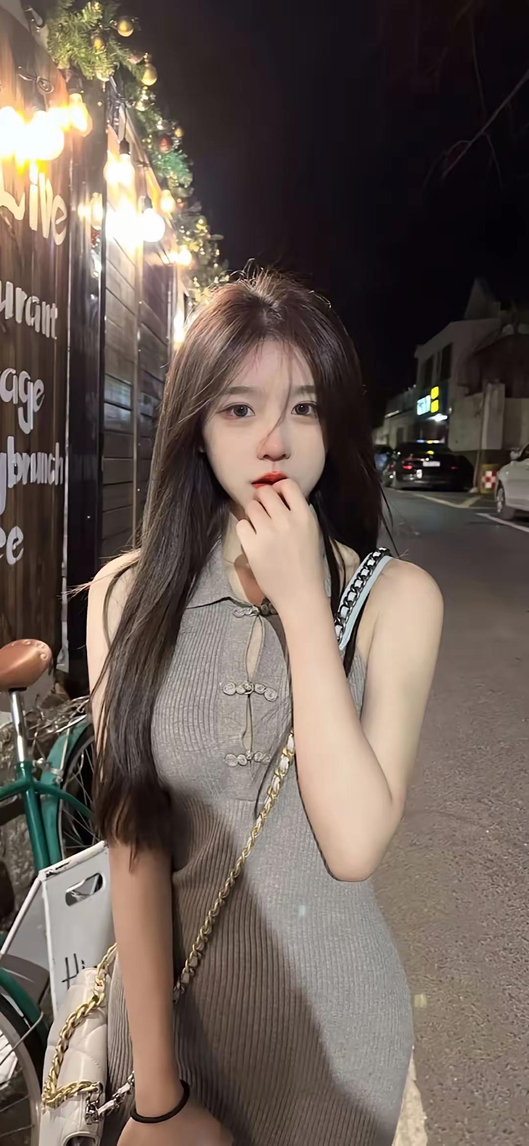 夜晚的街角，时尚少女轻抚发丝，背景灯光闪烁，散发迷人魅力。夜景气质少女 夜景女孩