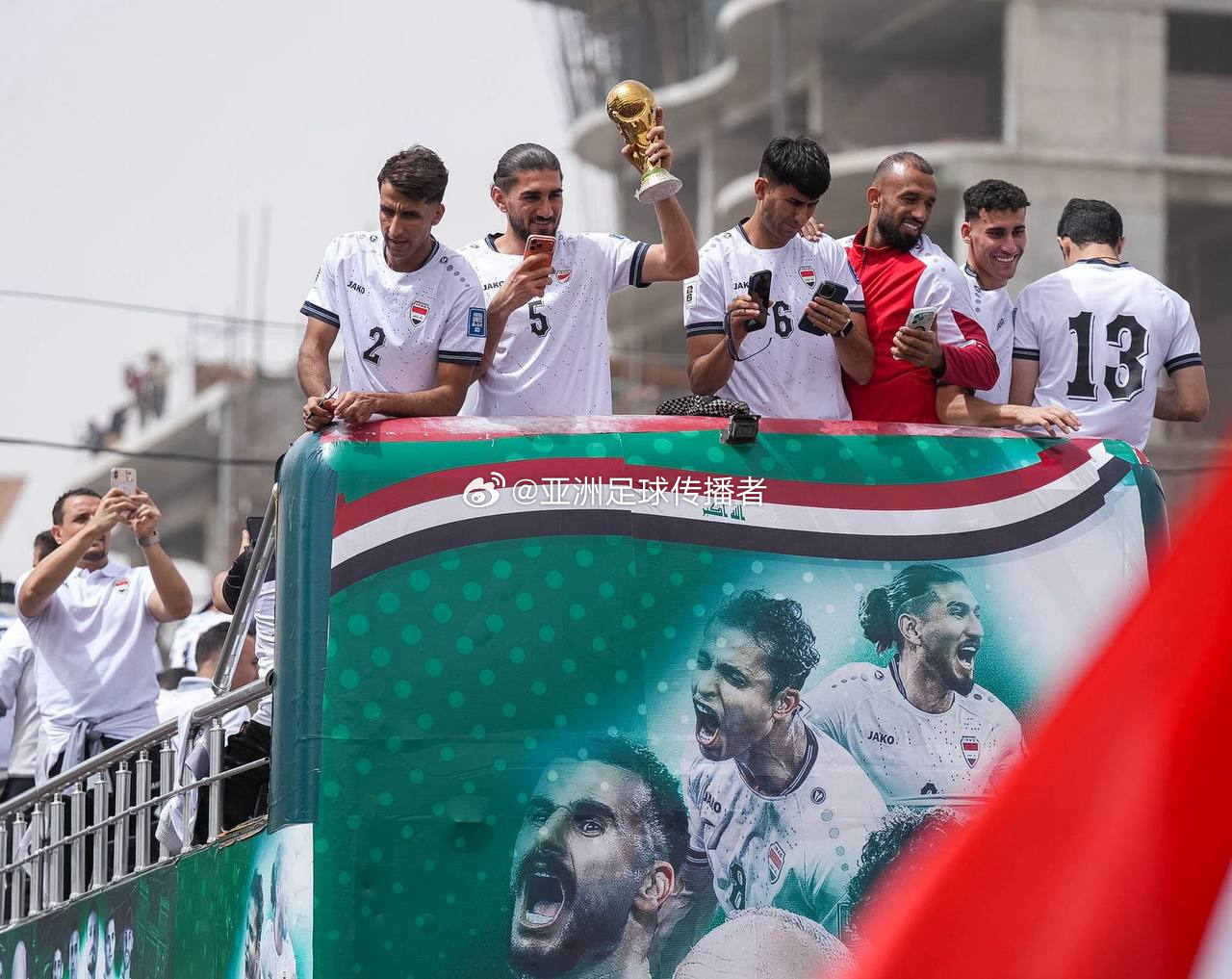 伊拉克国家队大巴在巴格达街头巡游，球迷们围拢过来欢呼庆祝 