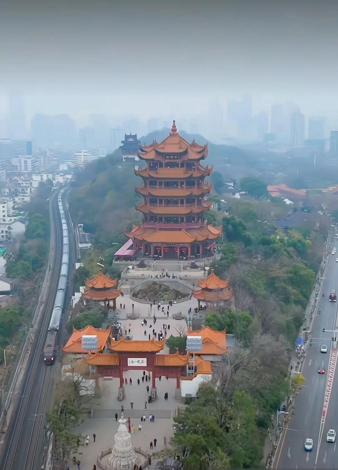 火车如巨龙从黄鹤楼边的蛇山腰呼啸而过，更像是蛇山中的蟒蛇出山了！