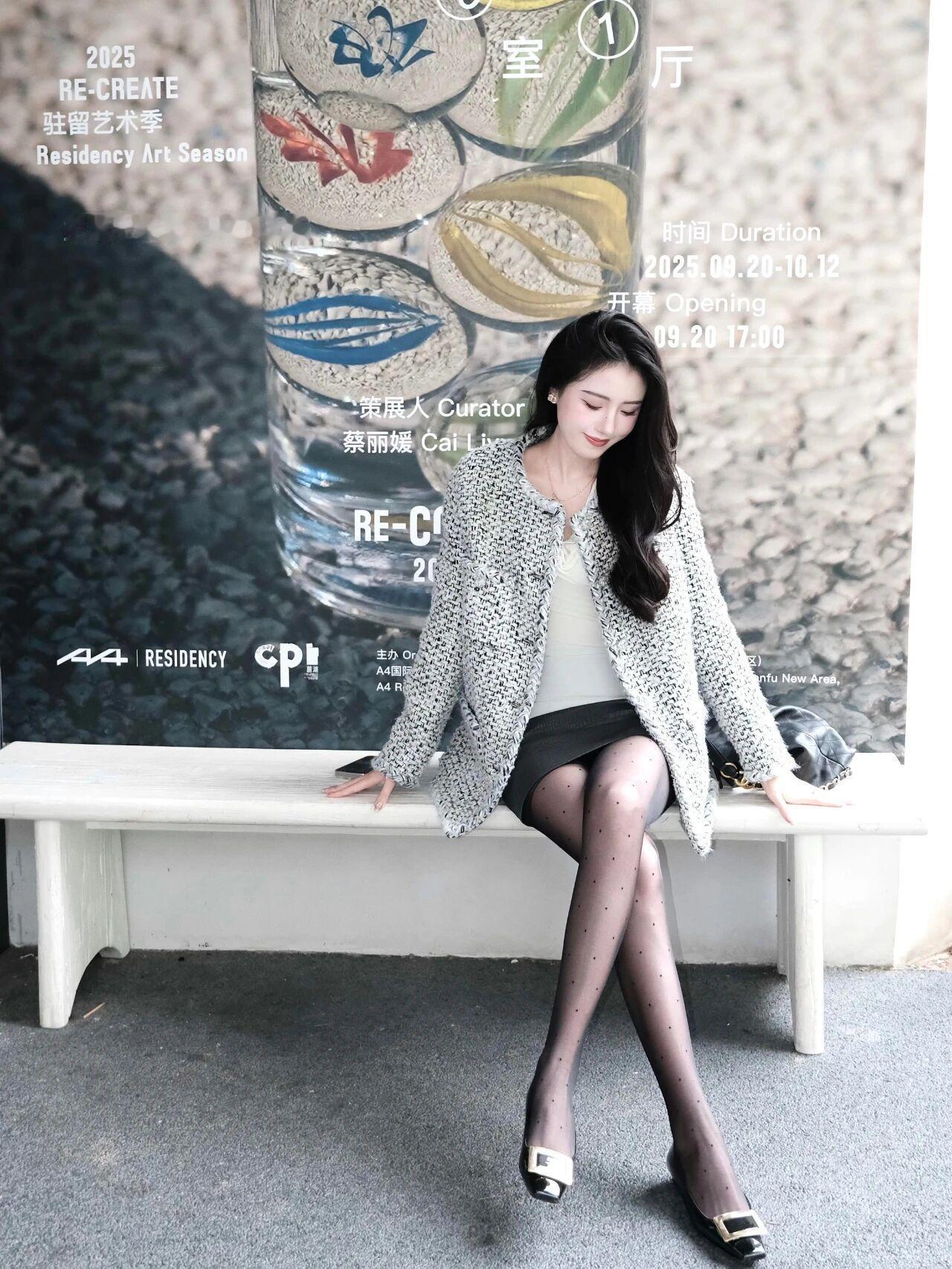 在这样一个充满艺术气息的环境中，一位女士优雅地坐在白色长凳上，成为了现场的一道亮