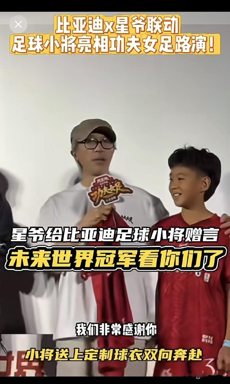 电影《功夫女足》路演现场，周星驰和比亚迪足球小将的互动。足球小将送上专属定制球衣