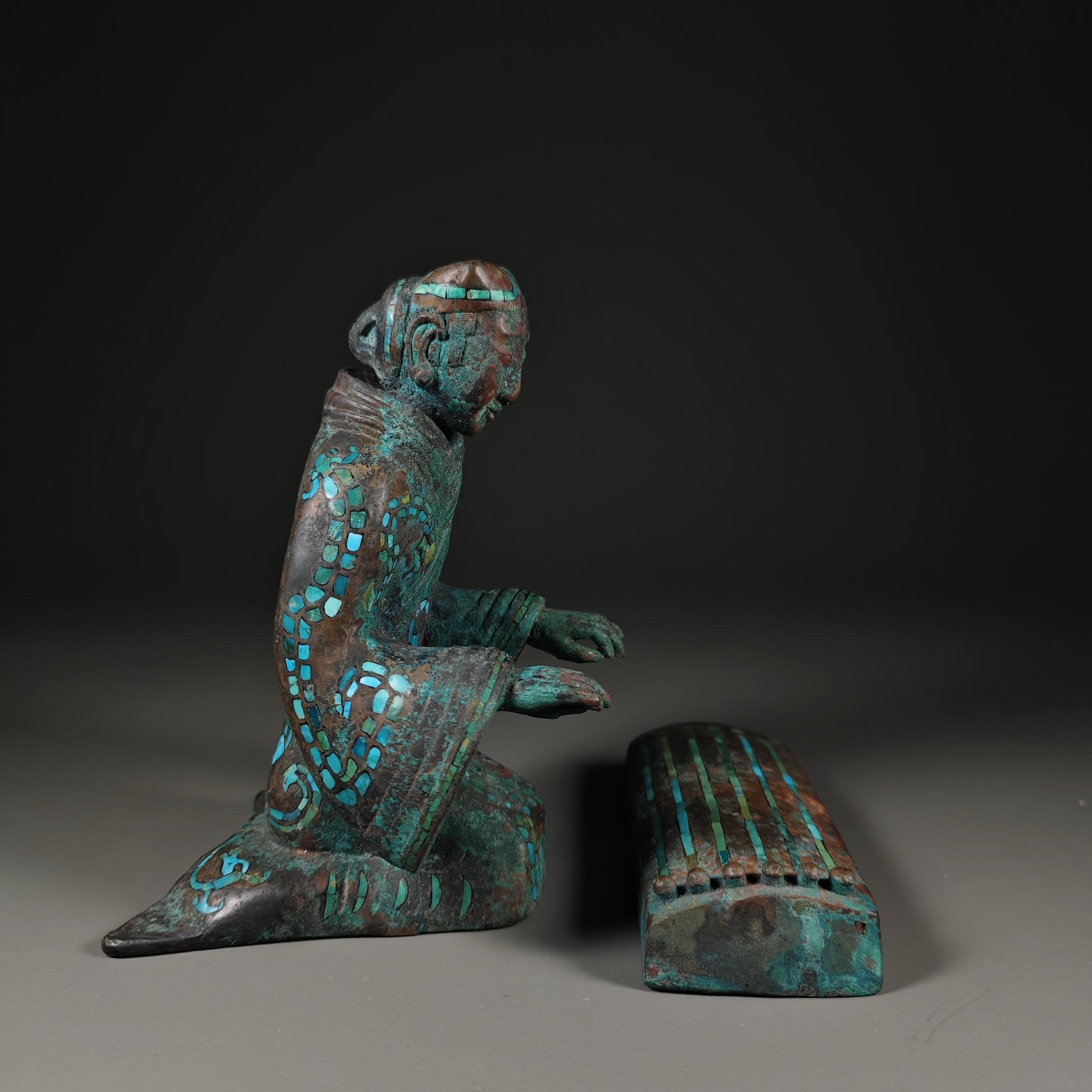 人物呈跪坐（“跽坐”）姿态，双手前伸，看起来像是在进行演奏或操作相关的...