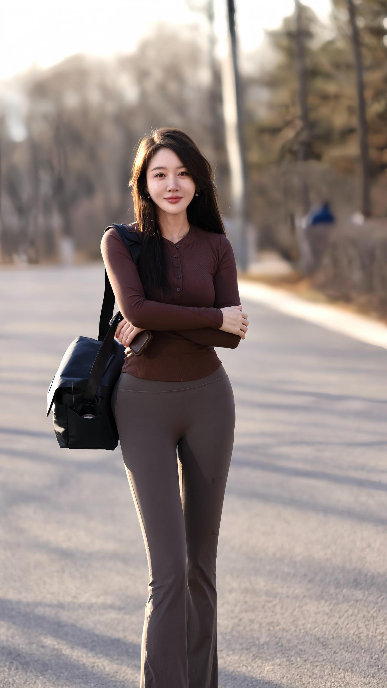 焦糖色的针织衫裹住初冬的风
深灰裤脚漫过路面的光影
她站在空阔的路上
双臂轻拢，