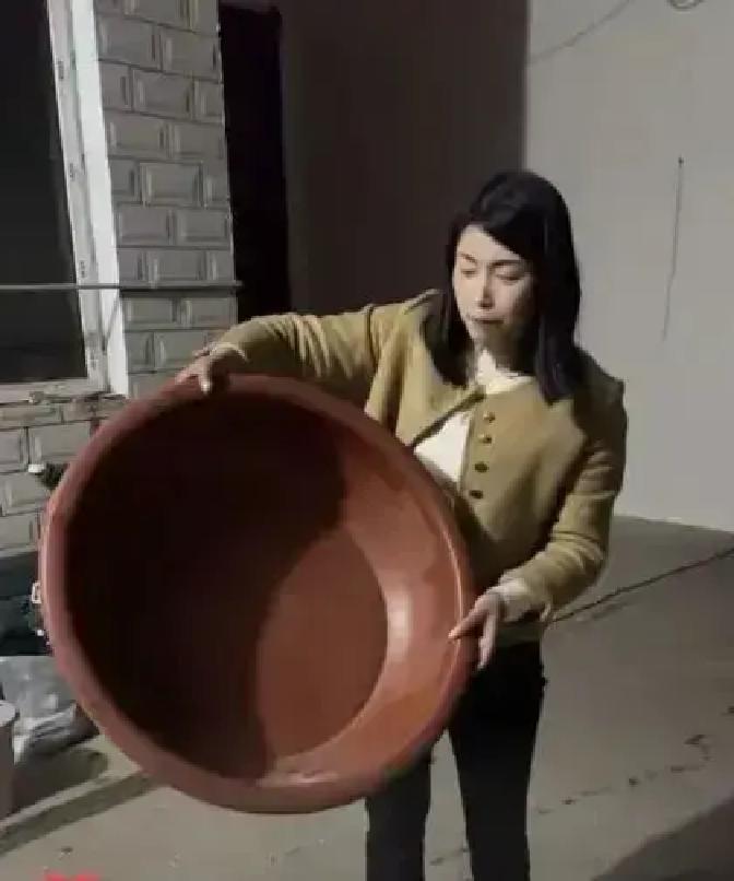 李女士把一只塑料盆用到42年，盆沿裂了三次，她用烙铁烫平继续装菜。

女儿周玲拍