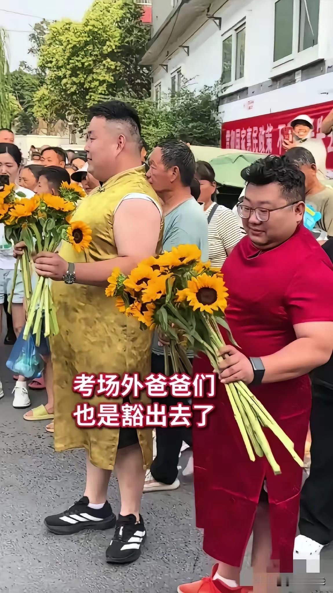 穿旗袍，举着向日葵，这样送考陪考，尤其是爸爸穿着旗袍，这已经是近几年来形成了一种