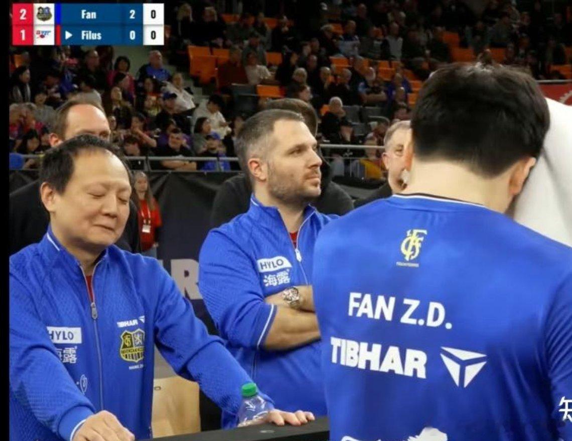 王志教练在暂停时面对樊振东放松暗爽的表情，嘴角压不住一点 