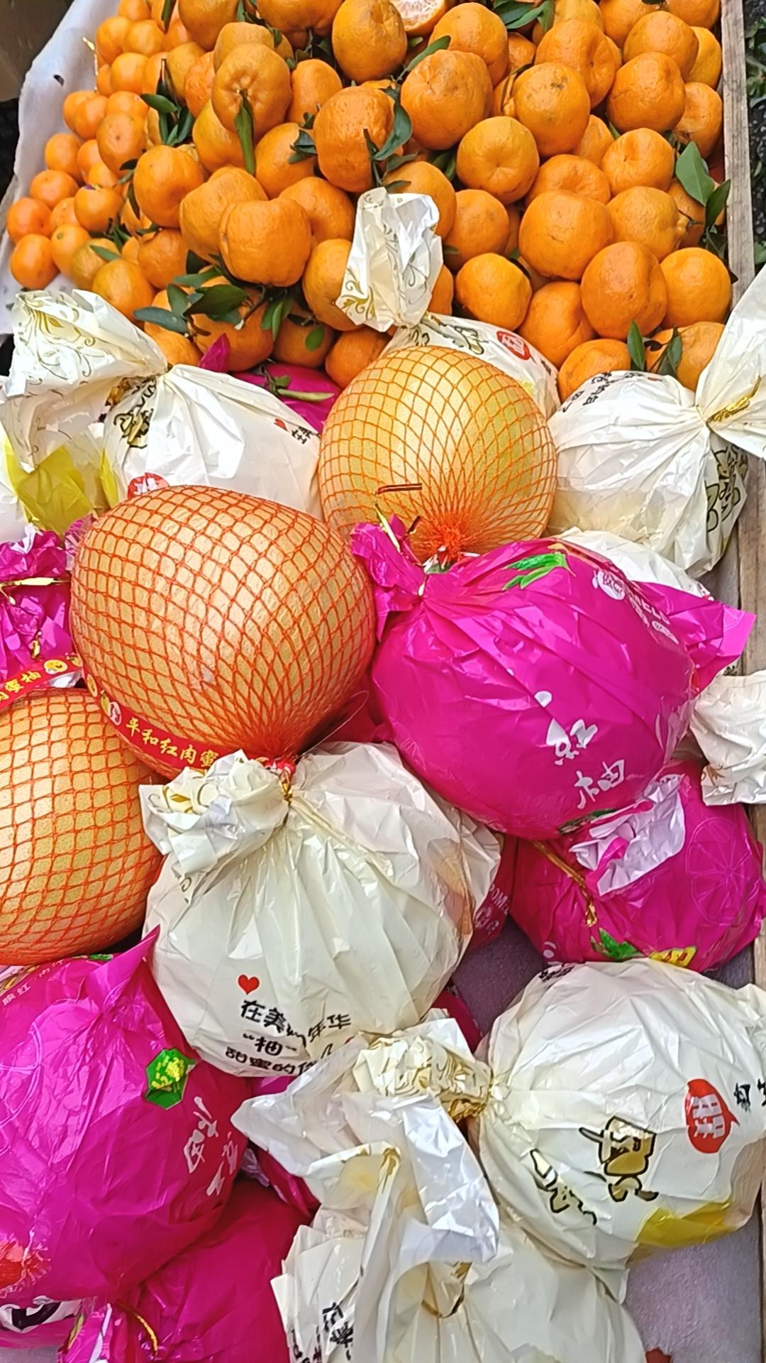 冬日的市集里，最惹眼的莫过于这堆得满满当当的橘柚摊。金灿灿的蜜橘簇拥着，橙黄的果