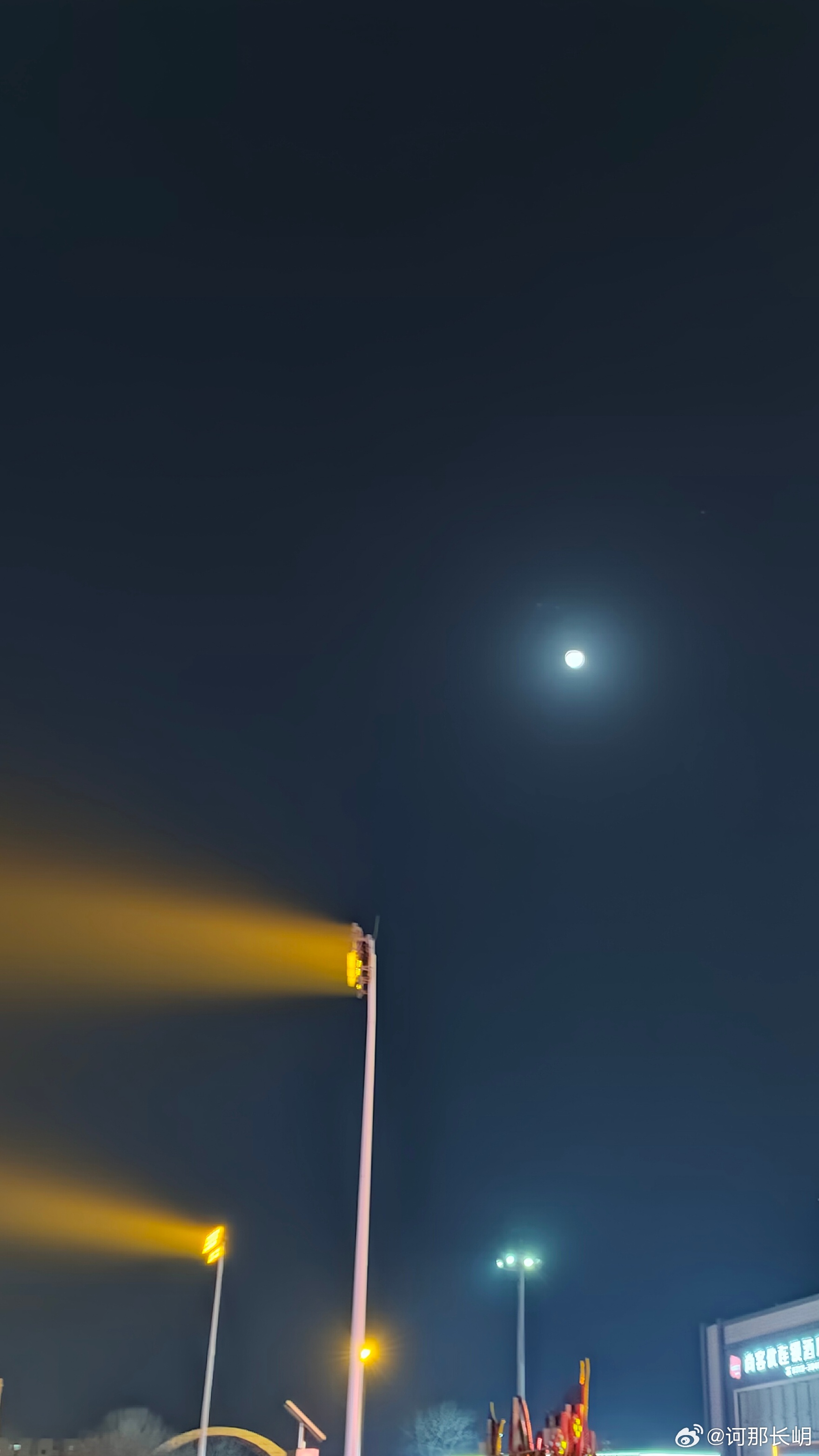 暮色沉浓，元宵的月色格外澄澈。路灯伫立如卫士，将暖金色的光带斜斜铺展，与高空的明