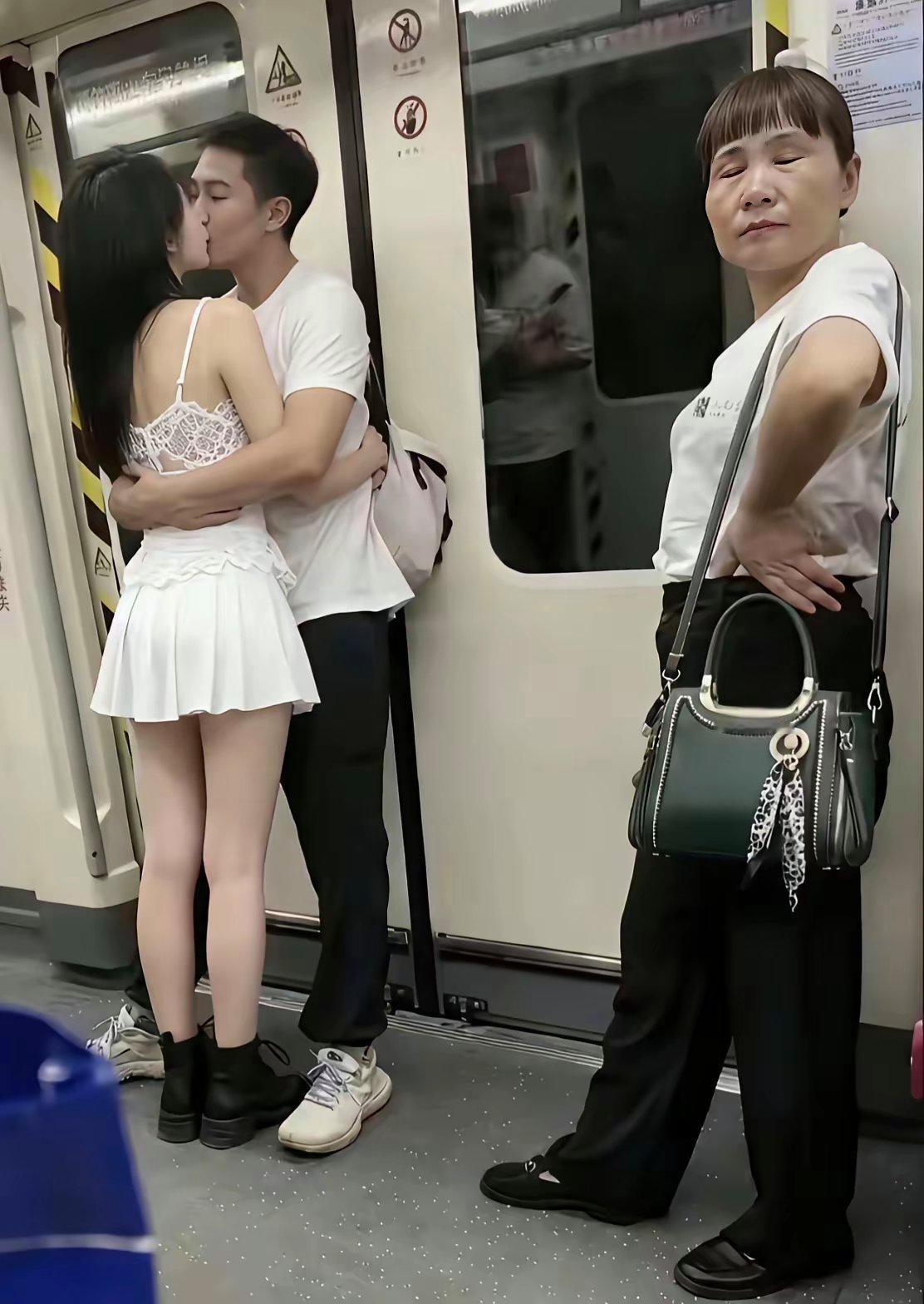 地铁上两个炙热的年轻人，进行疯狂的亲吻，旁边的大妈看到这一幕，深感不嗤且愤怒的闭