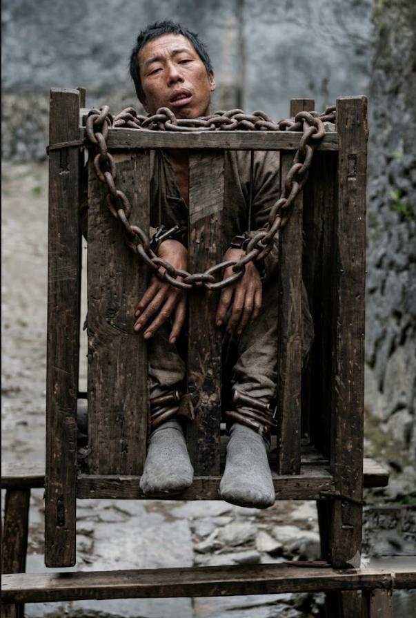 清末，一名被处以站笼（立枷）之刑的囚犯。
囚犯被完全禁锢在特制的立式木笼中，脖颈