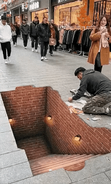 在这条步行街上，不可能出现这么一个大坑，这违背常理，因此可以断定，这不是真实的画