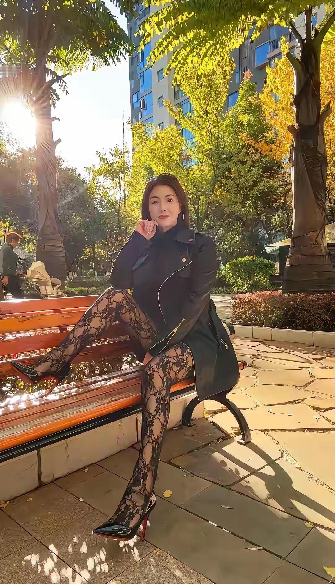 秋日暖阳下，红妆美人倚长椅。