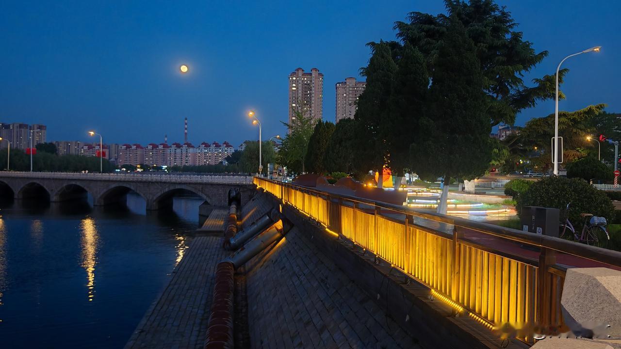 美丽的小城，灯火辉煌的夜晚，天空的月亮与灯火共明。