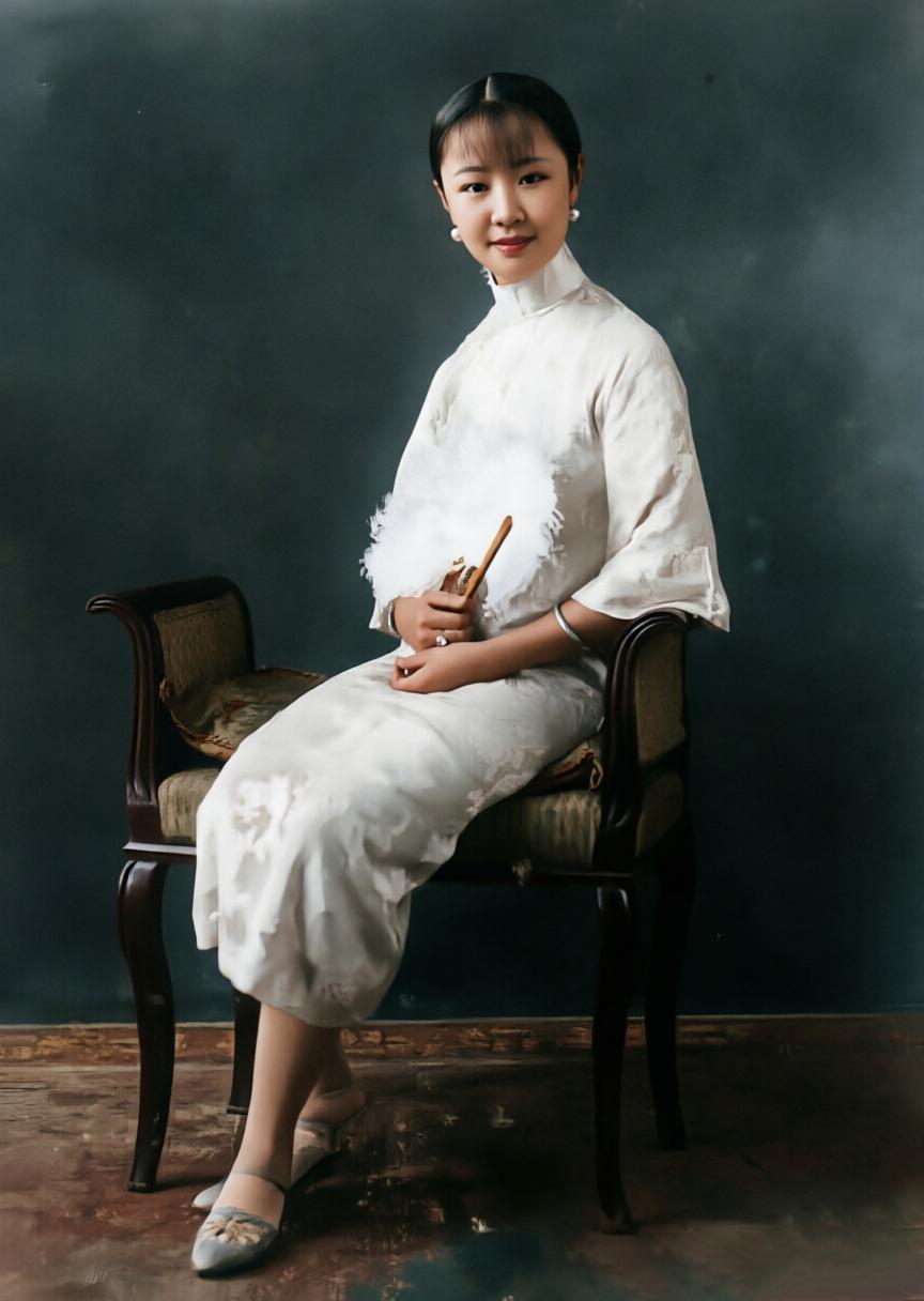 羽扇轻摇、素裙及膝，静坐于古典木椅之上。

1928年，天津日租界的张园，这帧老