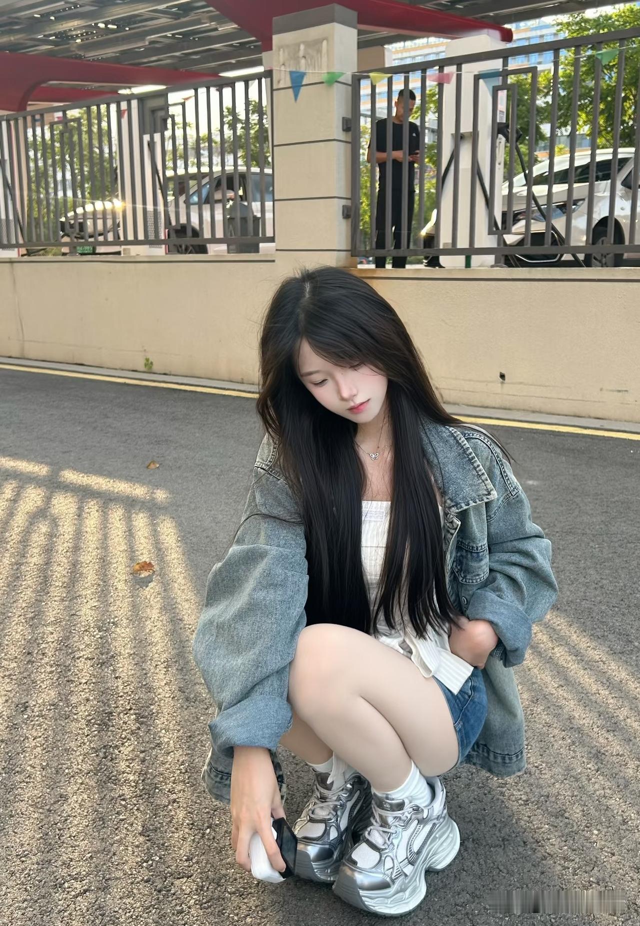 女生在路边低头玩手机。