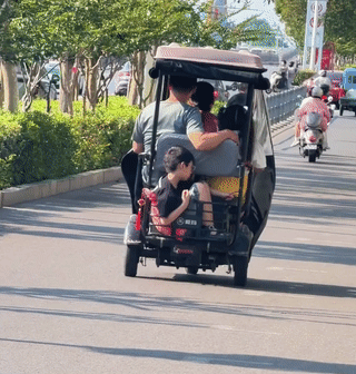 网友在路上拍到一家四口人乘电动车出门。
爸爸、妈妈和小女儿坐在前面的座位上。
而