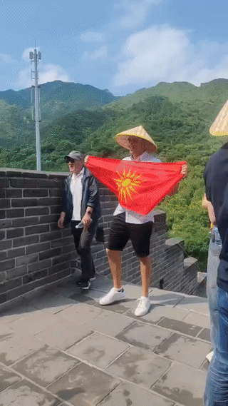 一名外国游客在游览中国长城的时候突然掏出来一面外国国旗对外展示？
有人认识这面国