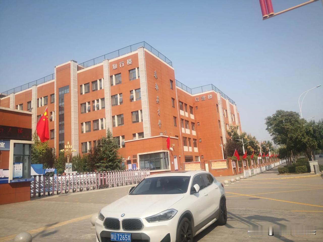  迎国庆，挂国旗。今日，路过咸阳市一学校。橘红色的教学楼，校门口栏杆上一面面迎风
