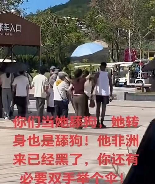 兄弟们，就这待遇你们享受过吗？小黑哥出门玩一趟，身后还有美女帮着撑伞，生怕太阳把