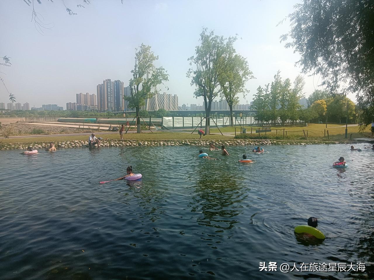 这是我今天在咸阳湖古渡公园里看到的一幕。虽然说是烈日当空，但在公园浅浅的溪流里许
