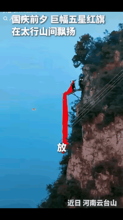 这是河南云台山，景区工作人员把一幅巨幅五星红旗，高高地悬挂在了太行山的悬崖峭壁之