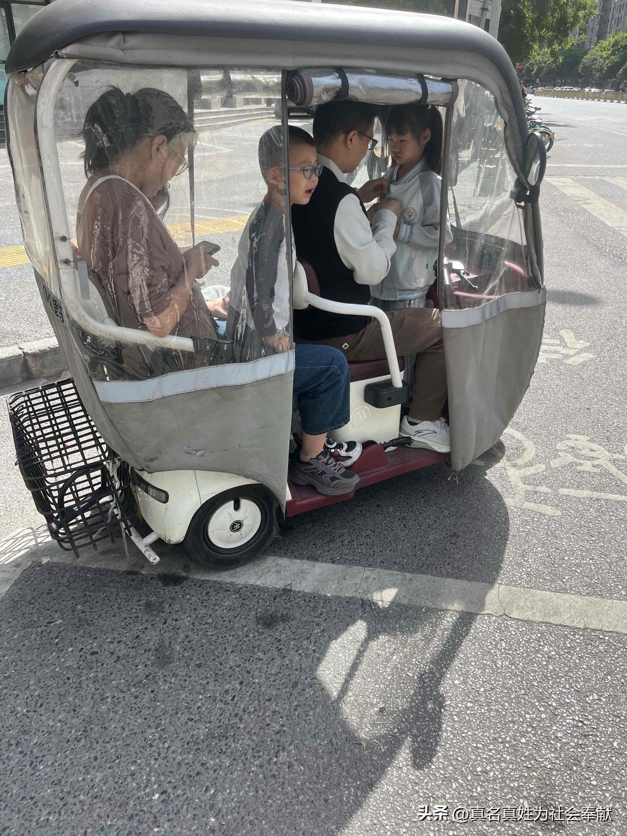 小小一辆电动三轮车，竟塞下了5个人，这位家长可真是心大，如此言传身教，实在有所偏