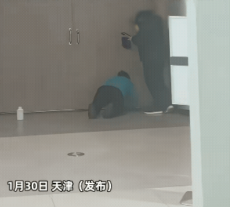 保洁阿姨跪在地上擦门缝里的灰尘，女子站着拍摄。
估计是拍完上传工作群的，也可能是