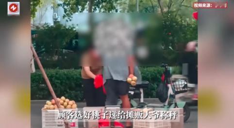 山东一女子在路边摊挑选桃子时，摊主大爷趁她不注意偷偷加了三个桃子进袋里，女子没察