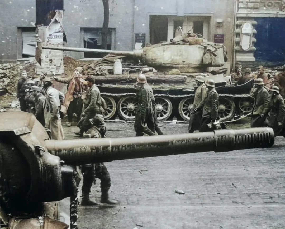 1945年，在柏林一群德国战俘经过苏军的ISU-152 和 T-34/85.