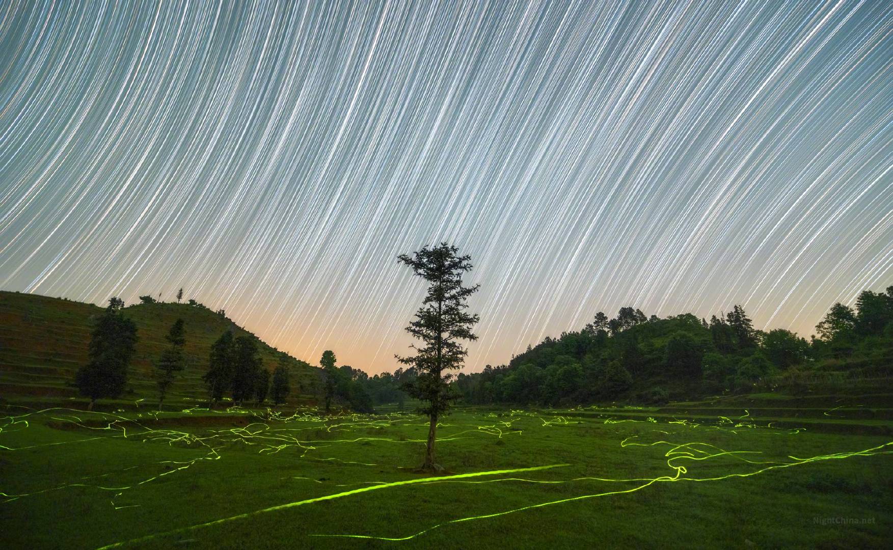 星轨与萤迹，一个在天，一个在地，各自流动，却在同一个夜晚、同一片山谷里相遇。天上