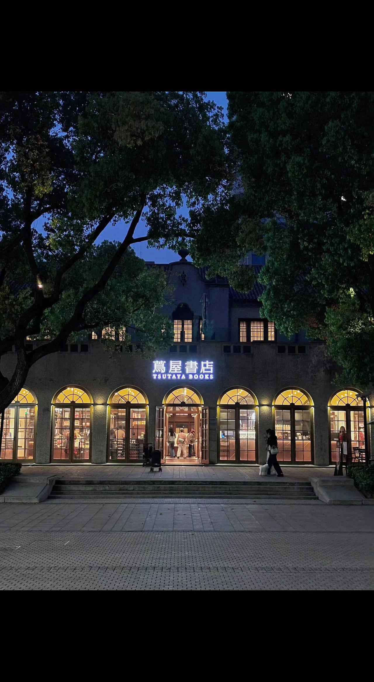 🌃暖黄灯光渗过拱形窗棂，老建筑在夜色里舒展书页📖。树影婆娑间，时间在这里慢成