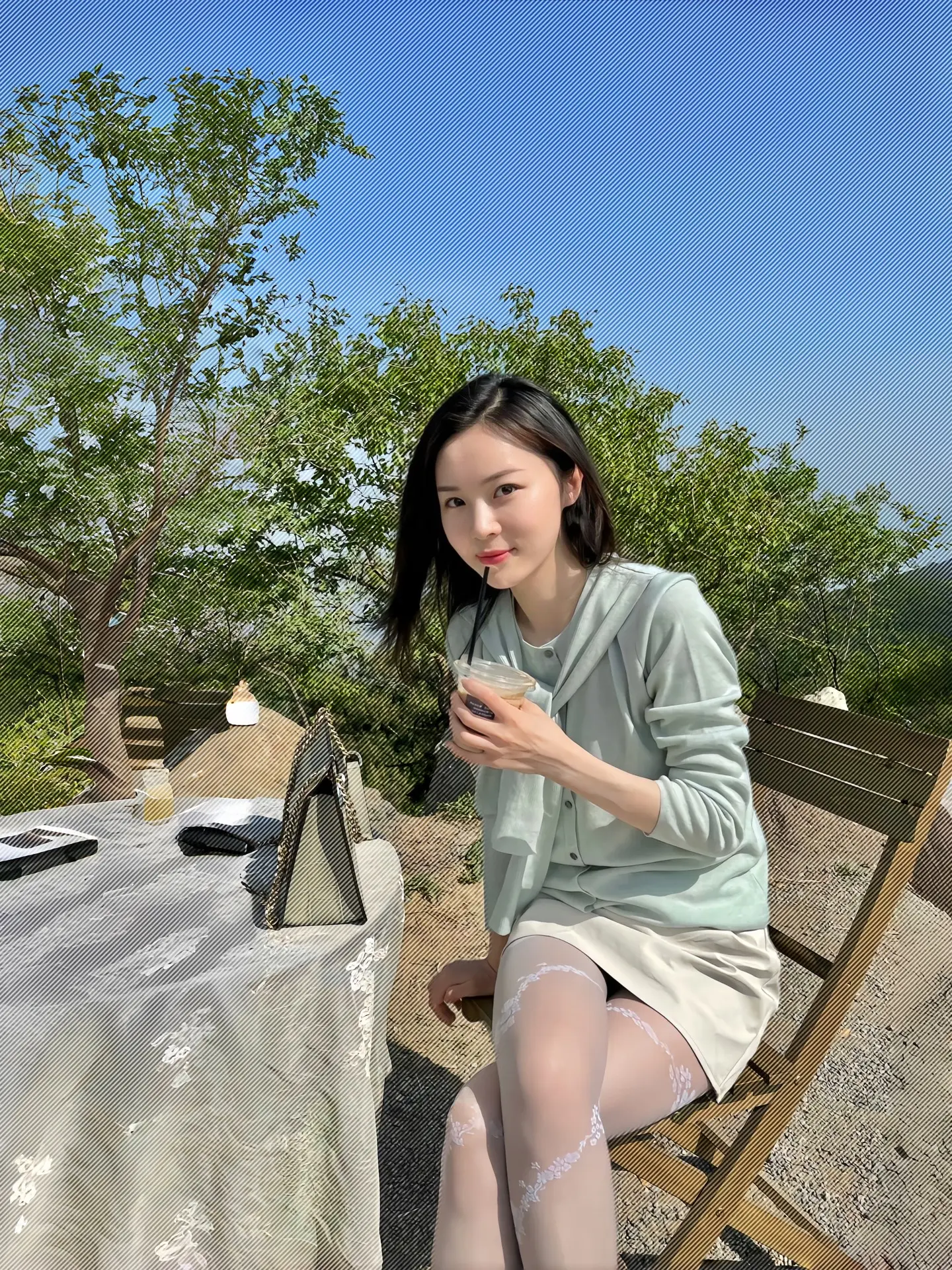 浅绿色的上衣和白色短裙，搭配着带有花纹的丝袜。头发披肩，看起来很自然。