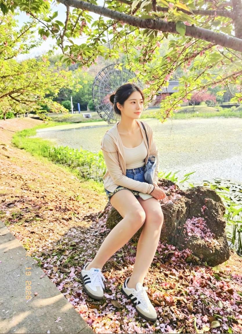 落樱铺满湖边小径，阳光透过枝叶洒下斑驳光影，风里带着青草与花香的气息。坐在湖边的