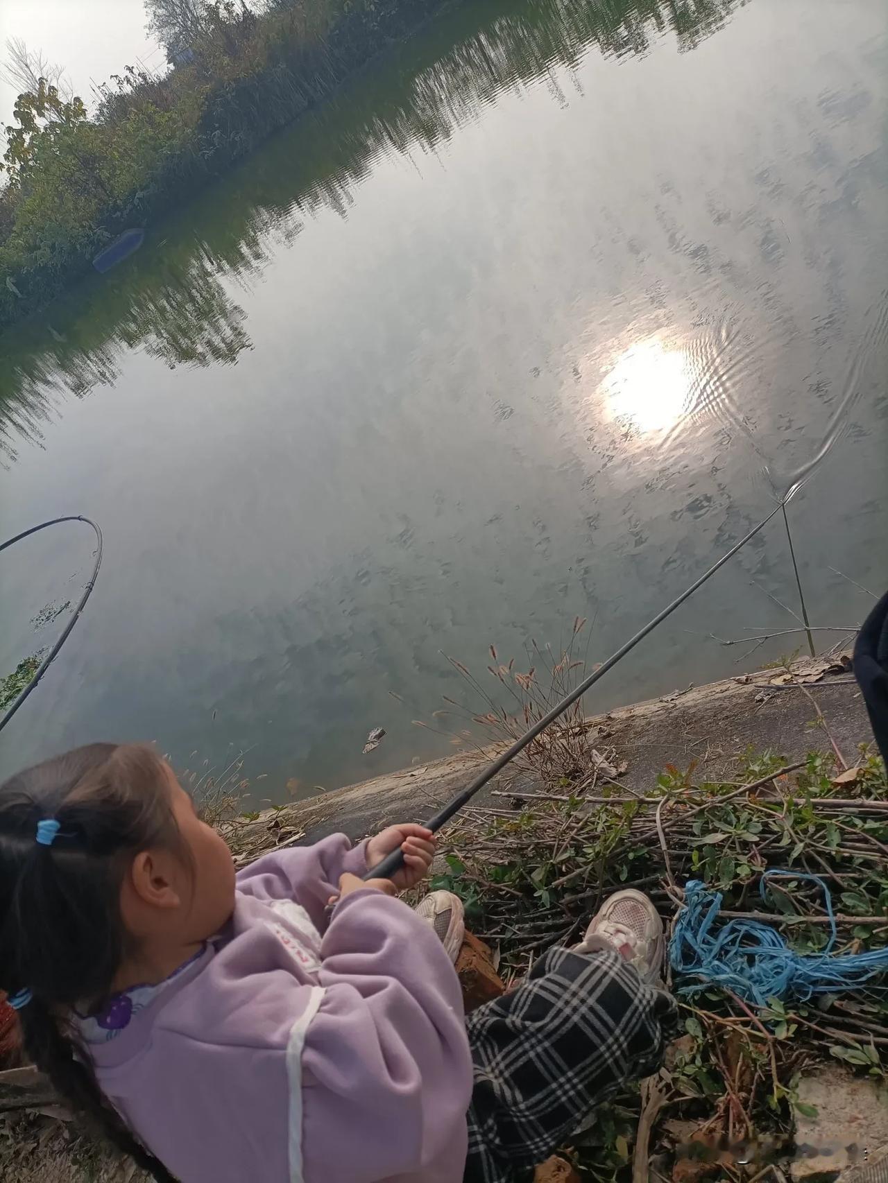 今天带小侄女去河边玩，这小家伙非抢我的鱼竿要钓鱼。你看她蹲在那草丛里，攥着竿子眼