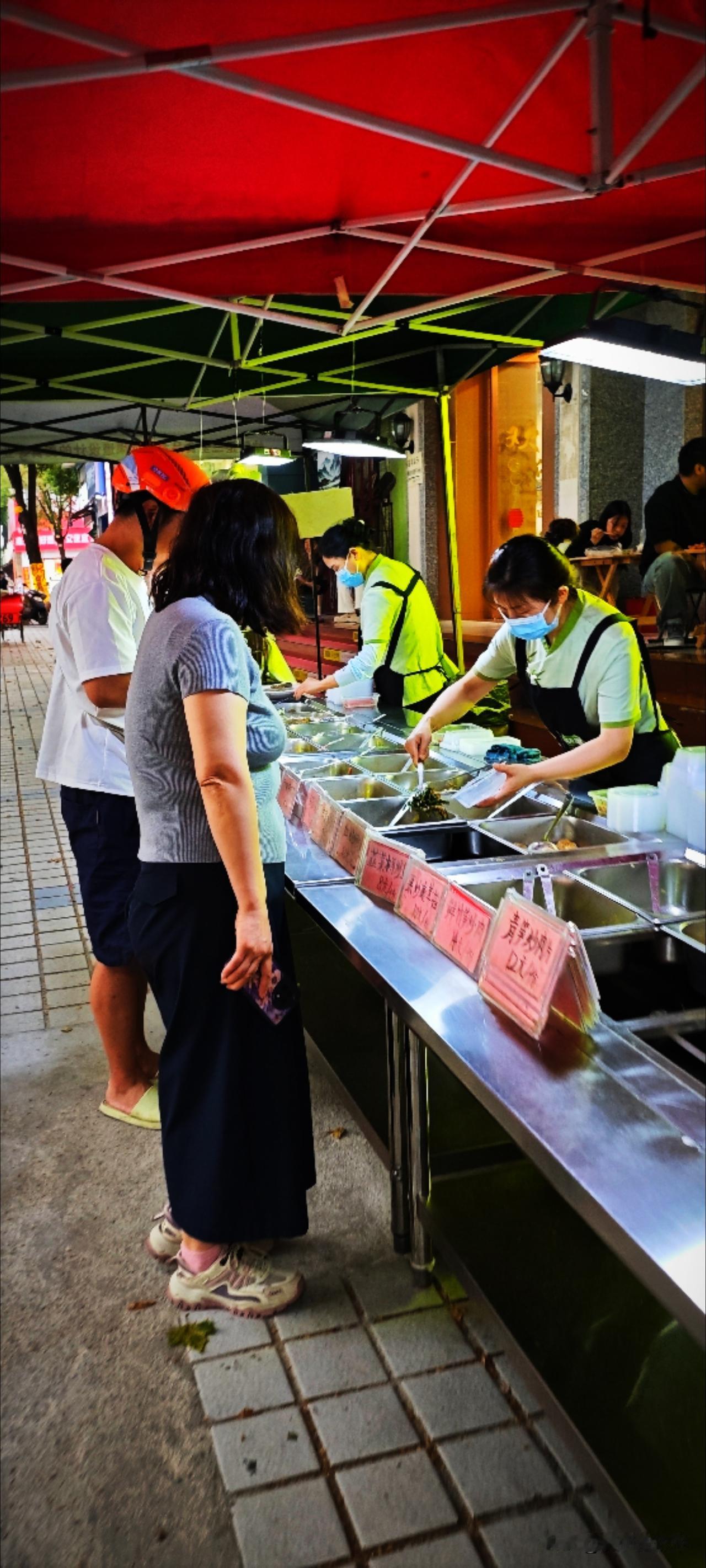 餐馆门口的快餐大棚每天都按时出餐，还在檐下摆了几张小桌马扎。老实说这家餐馆味道不