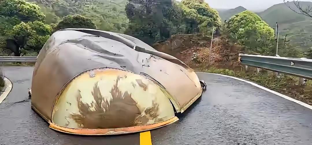 山东，一男子雨天开车途经山间弯道，刚转过一个急弯，突然，被一块巨大弧形金属构件拦