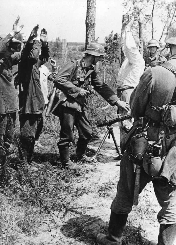 1941年，苏联，德国士兵对苏联战俘进行搜身。前景中的士兵配备了MG-34，第二...