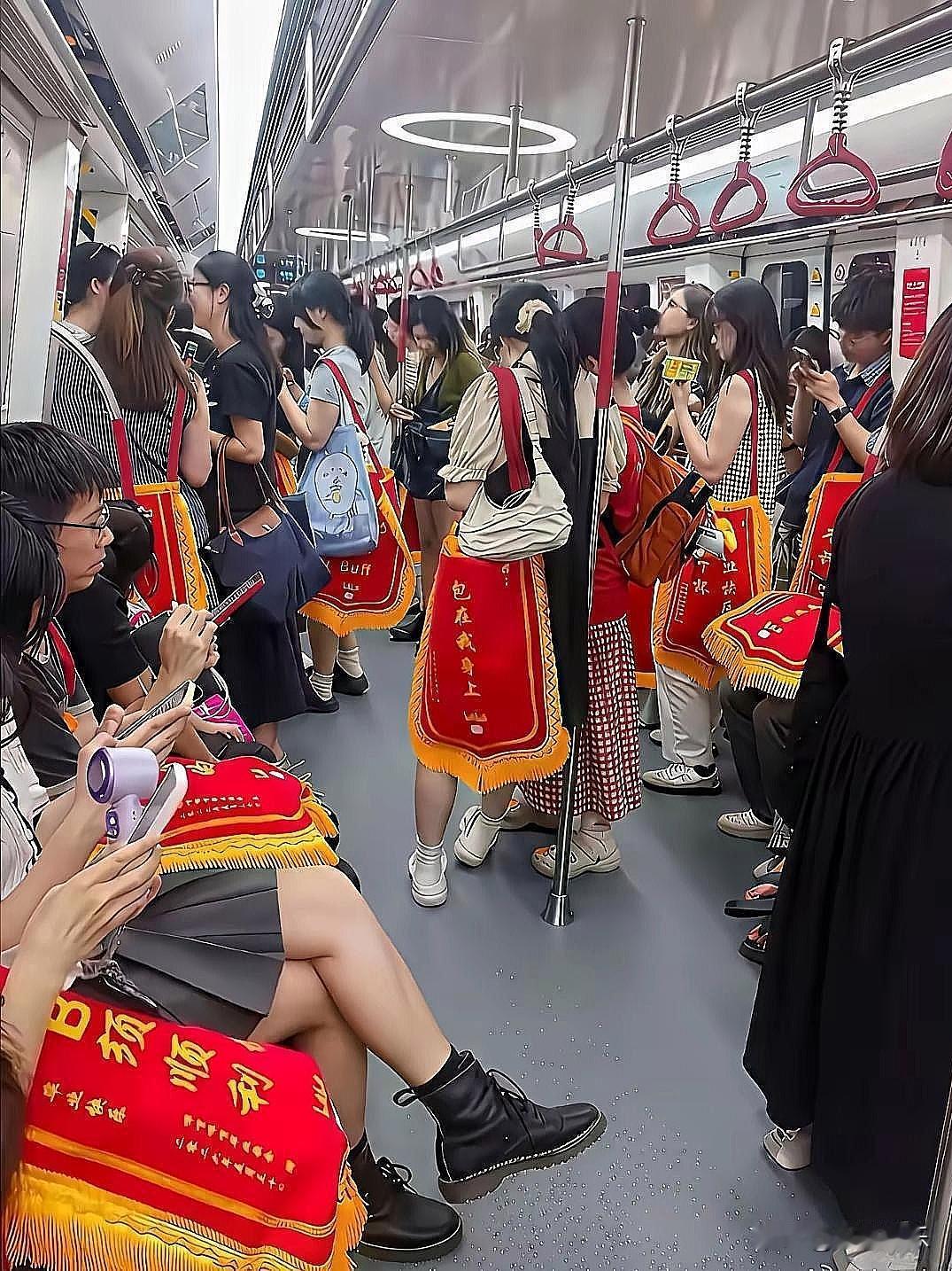什么情况地铁里这么热闹，一群年轻人背着带黄边的红色绶带，上面“包在我身上”“颈顺