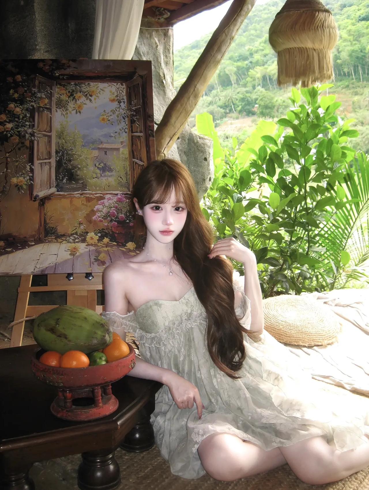 浅绿色碎花裙衬得皮肤白到发光，抹胸设计露出精致锁骨，坐在藤编垫子上，背景是油画和