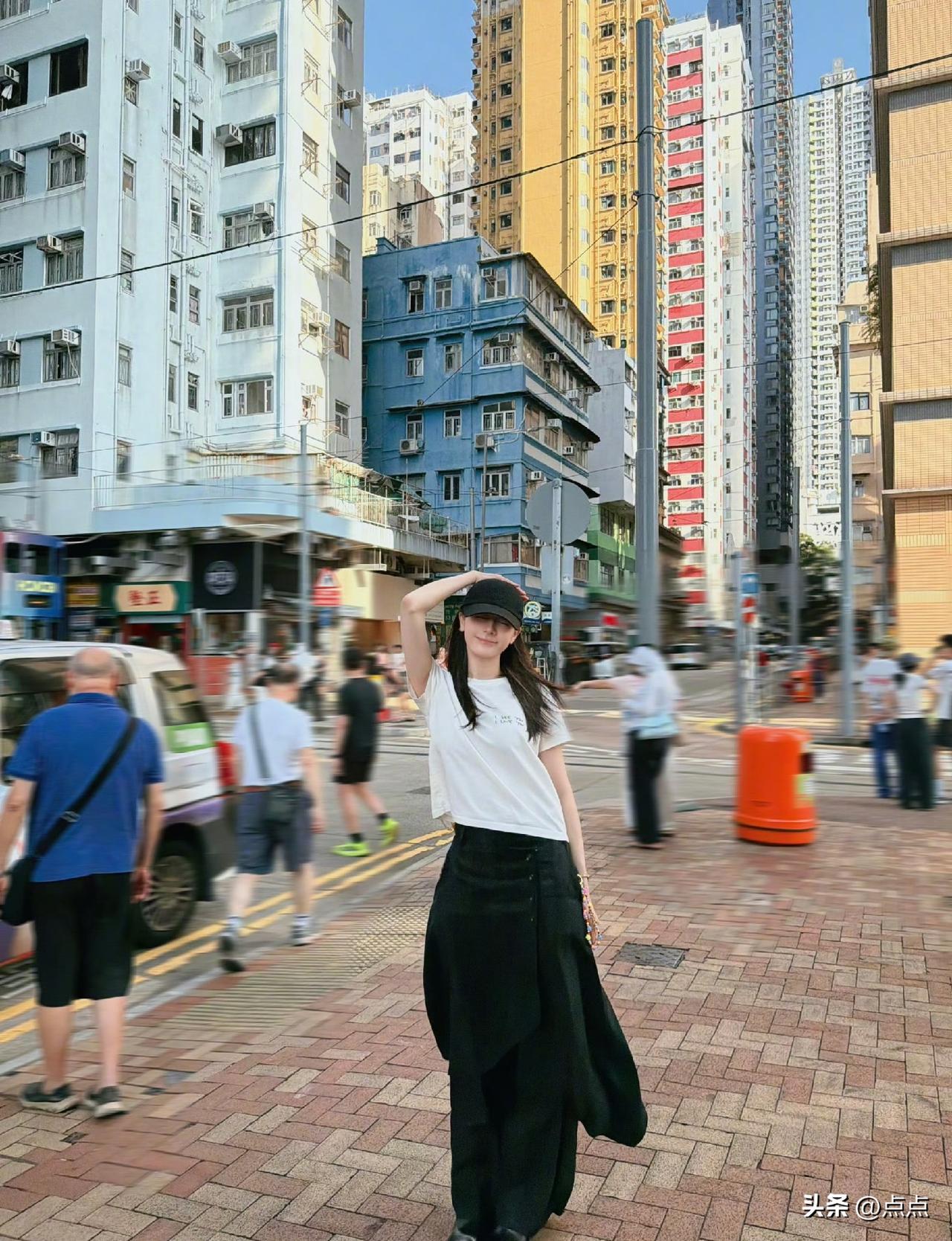 迪丽热巴分享香港街头三宫格随拍，配文“望左还是望右”，简约白上衣搭配黑长裙，随性