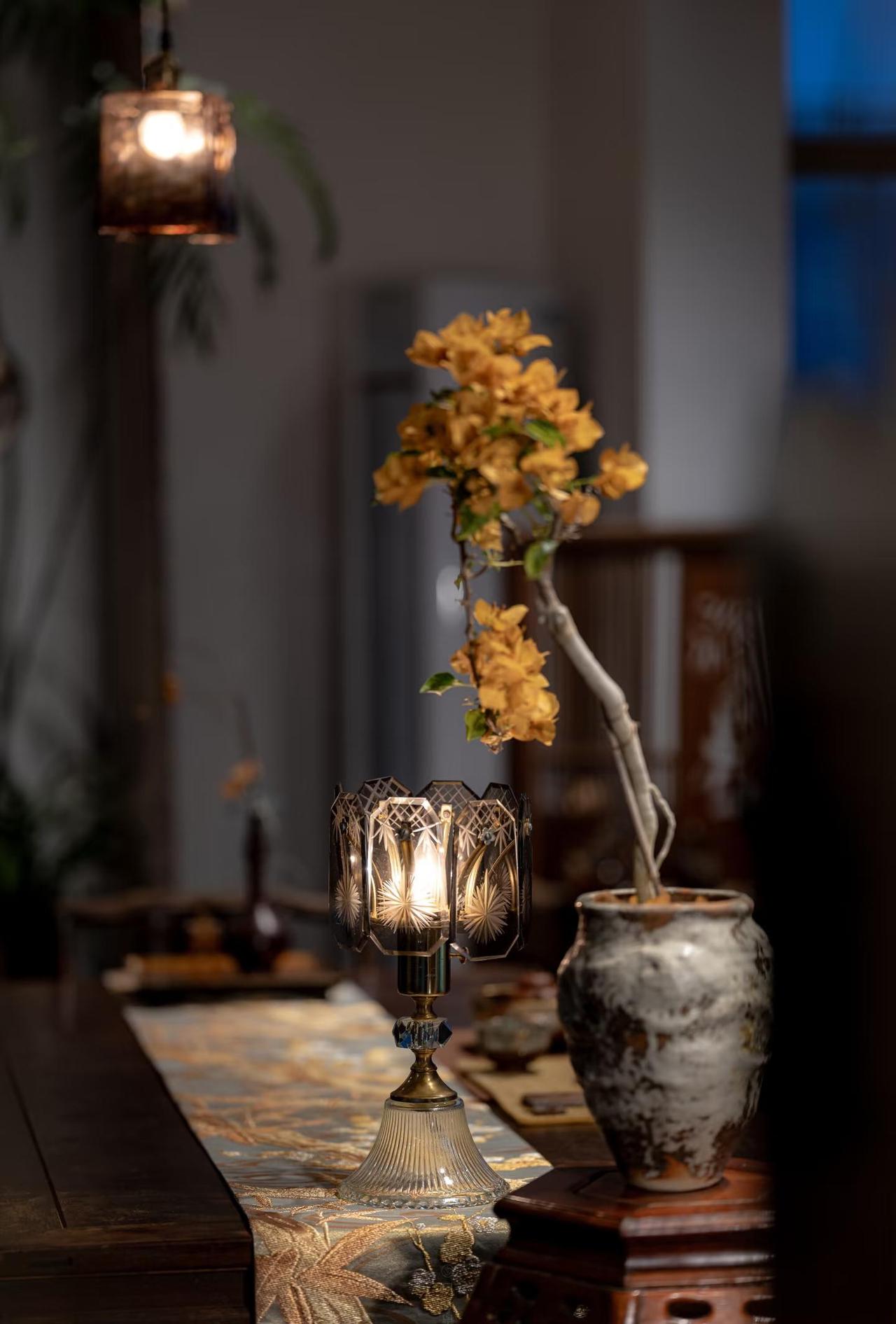 鎏金的岁月，铺作一席繁华。🧡
茶晶色琉璃灯泻下温光，三角梅在光晕里绽成另一盏明