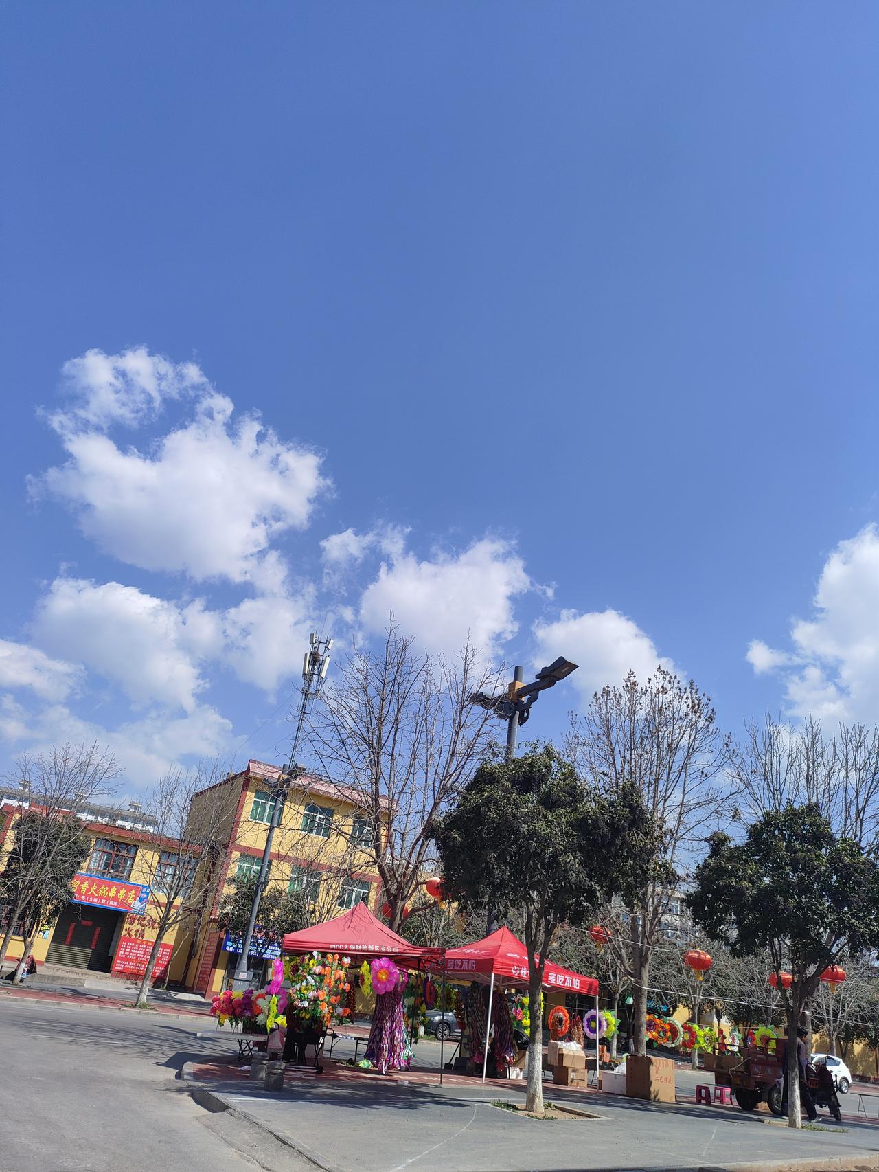 晴空万里，春风拂面，街头的红灯笼映着暖阳，烟火气里满是春日的明朗与踏实。