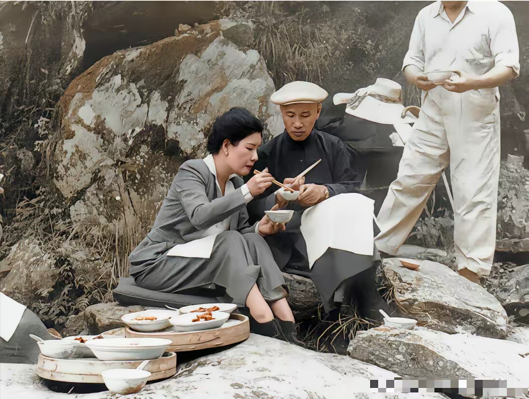 1946年夏，蒋介石与宋美龄于庐山黄龙潭野炊。蒋介石长衫软帽翻炒蛋炒饭，宋美龄着