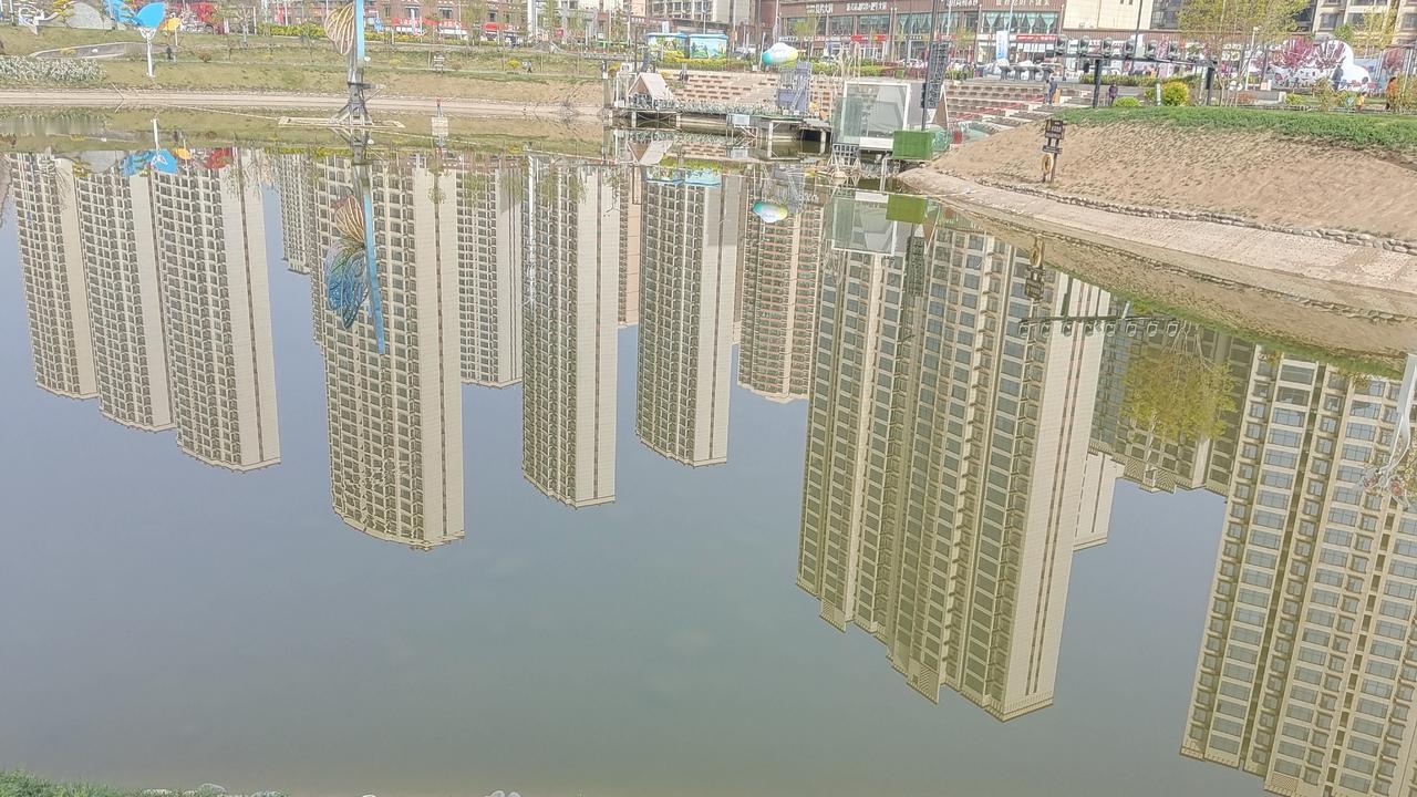 现代都市的倒影，静谧的湖面映照出繁华与宁静的对比。在这平静的湖面之上，高楼大厦的